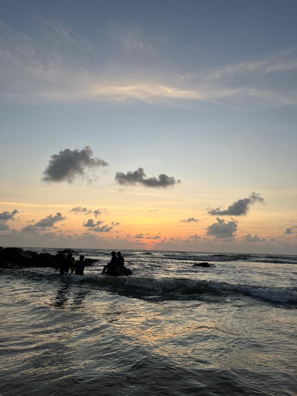 People enjoying the sea beneath a pastel sunset