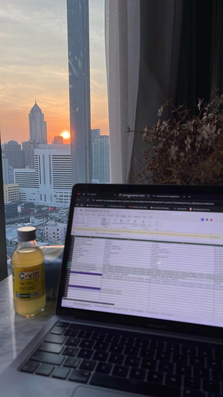 Laptop open beside a city sunset during a work session