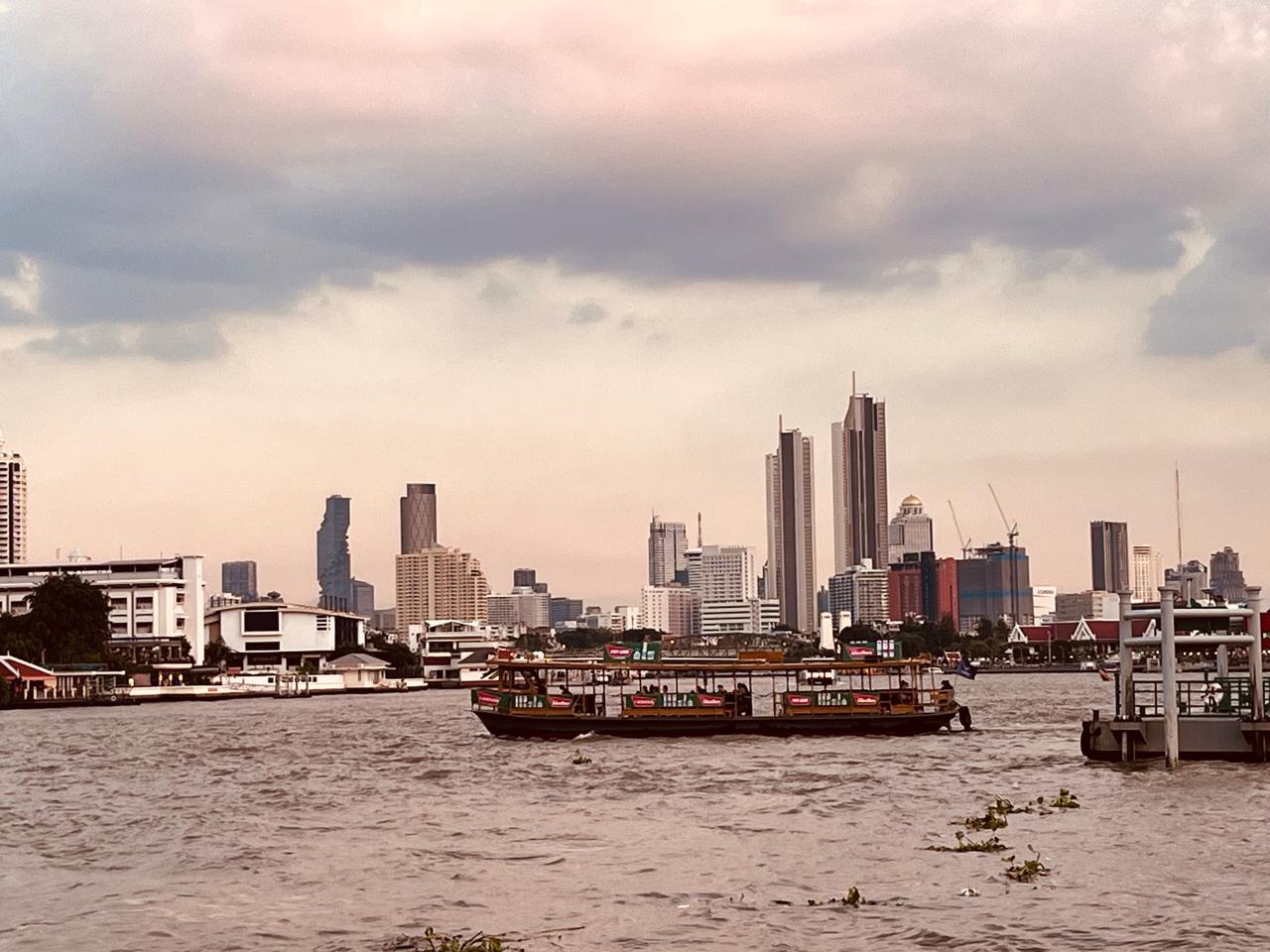 A river ferry crossing in front of the Bangkok skyline